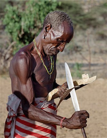 ritual - Kenya, Samburu District,  South Horr, Samburu District, Kenya. A ritual helper of a Samburu boy makes him new sandals the day before he is circumcised which he will wear for a month and then discard. Stock Photo - Rights-Managed, Code: 862-03366544