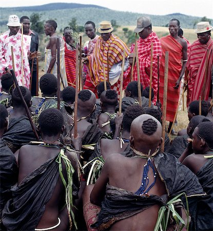 simsearch:862-03820649,k - Dressed in his black goatskin cloak,a Samburu boy puts his bundle of sticks,staves and gum on the roof of his mother's house. He has collected these with other boys from a special type of Commiphora tree during an arduous journey on foot of up to 200 miles. After his circumcision,he will make them into bows,blunt arrows and clubs. Foto de stock - Con derechos protegidos, Código: 862-03366540