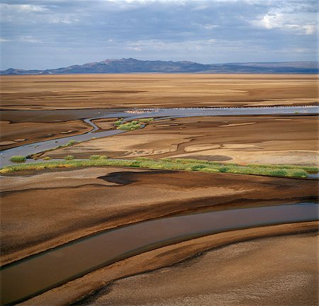 The mud or soil flats of the Sugata Valley looking north towards 'The Barrier'.'The Barrier' a volcanic ridge with two dormant volcanoes,which erupted towards the end of the 19th century - divides the exceedingly hot,barren Suguta Valley from Lake Turkana to its north. Stock Photo - Rights-Managed, Code: 862-03366582