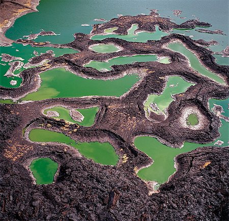 A series of lava rock pools are situated just off the southern end of Lake Turkana,northern Kenya's Jade Sea. The colour of the water is caused by extreme alkalinity in which green algae with a high chlorophyll content grows. Fotografie stock - Rights-Managed, Codice: 862-03366605