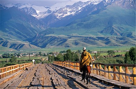 Kyrgyzstan,At-Bashi. Kyrgyz shepherd crossing a wooden bridge. At-Bashi,a small rural town,was said to have been built on top of settlements dating back to 8th century. It is considered to be one of the best places to see and buy Shyrdaks (felt carpets). Stock Photo - Rights-Managed, Code: 862-03367046