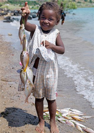 A Malagasy girl proudly holds up fish caught by her father from a fishing village just outside Antsiranana,more commonly known as Diego. Diego's deep-water harbour encircled by hills is of strategic importance to Madagascar. Foto de stock - Con derechos protegidos, Código: 862-03367258