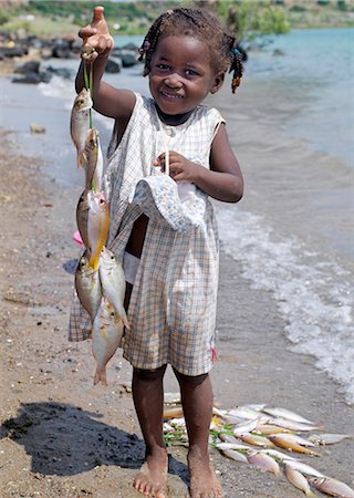 A Malagasy girl proudly holds up fish caught by her father from a fishing village just outside Antsiranana,more commonly known as Diego. Diego's deep-water harbour encircled by hills is of strategic importance to Madagascar. Stock Photo - Rights-Managed, Code: 862-03367258