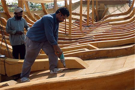 Boat builders constructing a large dhow in the boat yard at Sur Foto de stock - Con derechos protegidos, Código: 862-03360198