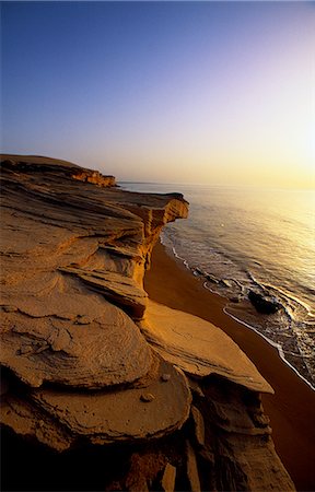 Aeolianite cliffs where the Wahiba Sands meet the Arabian Sea. Here the erosive action of the sea has exposed strange formations in these ancient,lithified dunes. Foto de stock - Direito Controlado, Número: 862-03360256