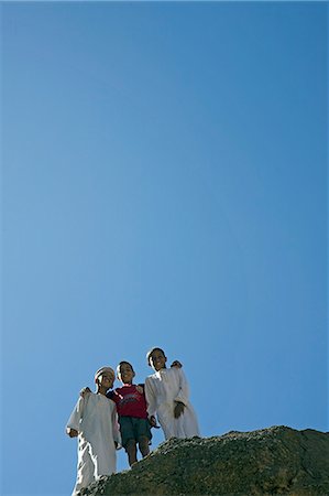 simsearch:862-03437293,k - Oman,Western Hajar Mountains. In a remote mountain village,young boys pose for the camera atop a rocky ridge of sedimentary rock. Foto de stock - Con derechos protegidos, Código: 862-03360315