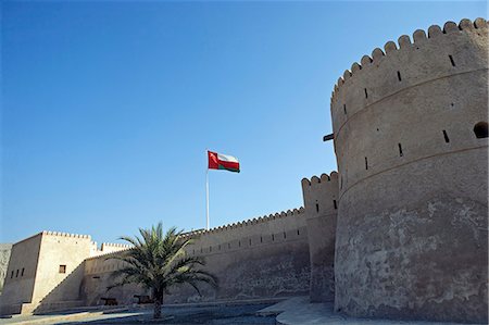 flags of the middle east - Oman,Musandam Peninsula,Khasab. A traditional mud built fort overlooking the bay to the front of the small town of Khasab famous for fishing and smuggling in small,fast boats,to and from Iran. Stock Photo - Rights-Managed, Code: 862-03360322
