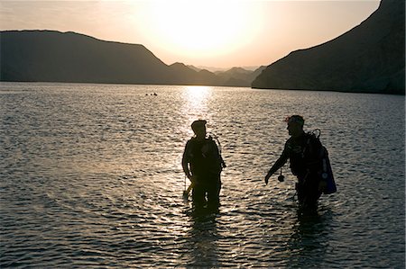 simsearch:862-03437387,k - Oman,Muscat Region,Bandar Khayran. As the sun sets two divers exit the water after and evening dive on one of Omans many tropical reefs. Fotografie stock - Rights-Managed, Codice: 862-03360338