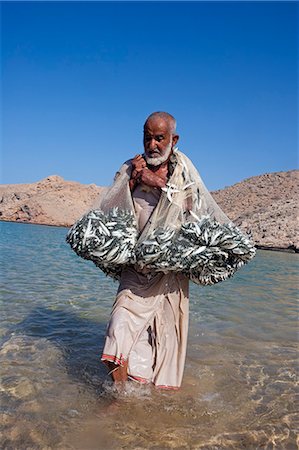Oman, Mascate région, Bandar Khayran. Un vieux pêcheur des poissons pour les sardines avec un filet traditionnel d'une plage sur la côte près de Muscat Photographie de stock - Rights-Managed, Code: 862-03360332