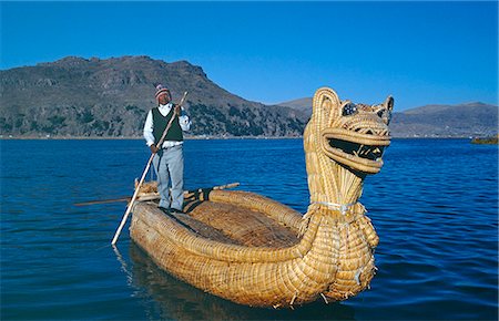 An Indian man from the Uros Islands,islands made from floating reeds,poles his reedboat across Lake Titicaca Stock Photo - Rights-Managed, Code: 862-03360446