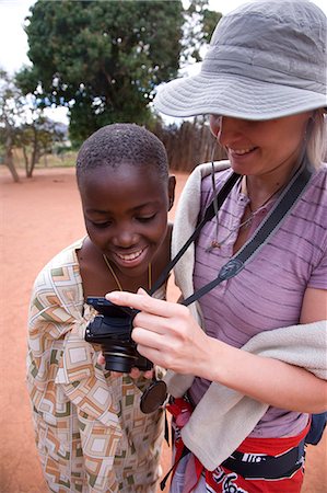 A tourist shares a photo with a local child in a village in Milwane Game Reserve,Swaziland. Stock Photo - Rights-Managed, Code: 862-03361235