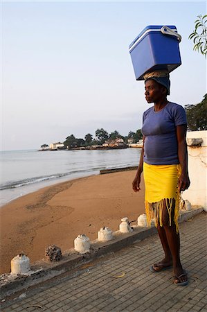 simsearch:862-03361282,k - A street seller walks along the 'Baia de Ana Chaves' (Bay of Ana Chaves. Ana Chaves was a renowned rich black slave trader who lived in sao Tomé in the 1600's). Sao Tomé and Principé is Africa's second smallest country with a population of 193 000. It consists of two mountainous islands in the Gulf of New Guinea,straddling the equator,west of Gabon. Stock Photo - Rights-Managed, Code: 862-03361309