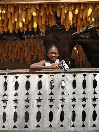 Une fille malgache avec épis de maïs suspendus pour sécher du balcon d'une maison de deux étages typique de Betsileo, Madagascar. Photographie de stock - Rights-Managed, Code: 862-03363987