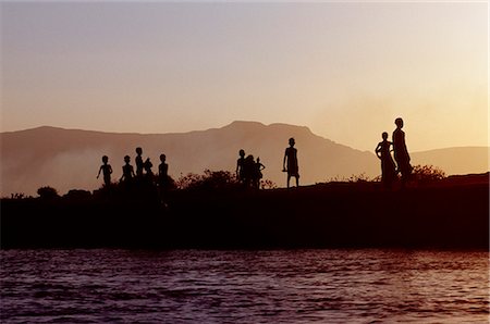 simsearch:862-03354002,k - Dassanech children play on the bank of the Omo River at sunset. Much the largest of the tribes in the Omo Valley numbering around 50,000,the Dassanech (also known as the Galeb,Changila or Merille) are Nilotic pastoralists and agriculturalists. Foto de stock - Con derechos protegidos, Código: 862-03437081