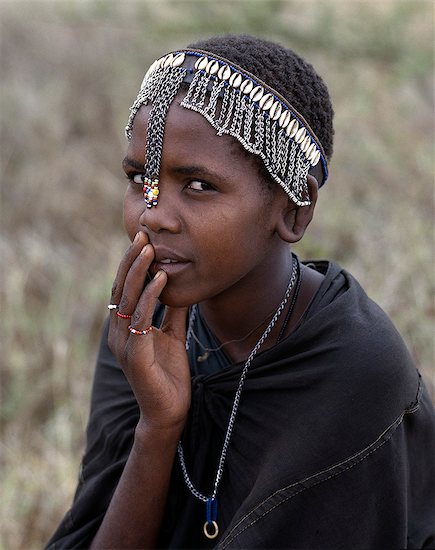 A young Maasai girl wears a headband decorated with chains and cowrie shells that signifies her recent circumcision. Clitodectomy was commonly practiced by the Maasai but it is now gradually dying out. Stock Photo - Premium Rights-Managed, Artist: AWL Images, Image code: 862-03437161
