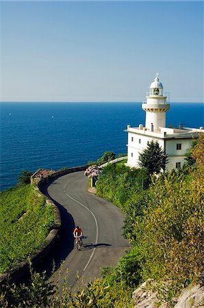 simsearch:862-03354288,k - San Sebastian Bay Clifftop Lighthouse with Cyclist Riding uphill Foto de stock - Direito Controlado, Número: 862-03437377