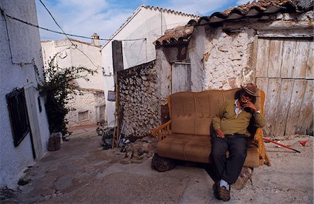 simsearch:862-03354522,k - Spain,Andalucia,Sierra de Segura,Hornos (aka Hornos de Segura). A man enjoys a cigarette on a sofa outside his house. Foto de stock - Con derechos protegidos, Código: 862-03437380