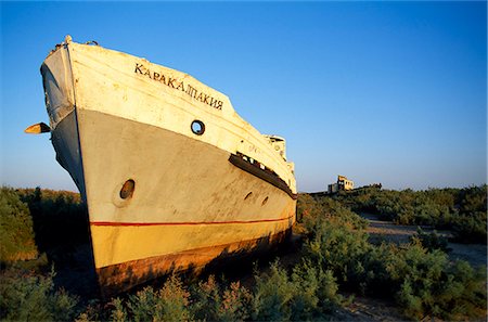 The rusting hulls of old Russian ships lie abandoned on the dried out bed of what was once the Aral Sea. Stock Photo - Rights-Managed, Code: 862-03437669