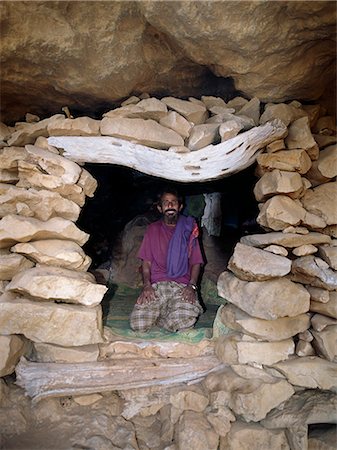 A comfortable rock shelter dwelling of a pastoral Bedu man in the Haghir Mountains. Caves and overhanging rocks are used extensively by pastoralists who make up the majority population of the island’s interior. Families will often own a conventional stone house in the lowlands too. Foto de stock - Con derechos protegidos, Código: 862-03437918