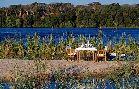 dinner in water - Zambia,Livingstone. The River Club - honeymoon lunch set up on island in the Zambezi River in front of the lodge. Stock Photo - Rights-Managed, Code: 862-03437946