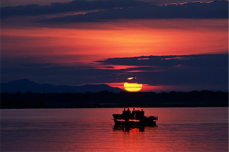 Zambia,Lower Zambesi National Park. Guests watching the sun rise over the Zambezi River from a boat. Stock Photo - Rights-Managed, Code: 862-03437965