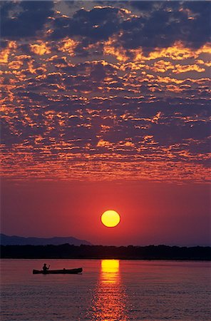 sunset safari - Zambia,Lower Zambesi National Park. Canoeing on the Zambezi River at sun rise under a mackerel sky. Stock Photo - Rights-Managed, Code: 862-03437966