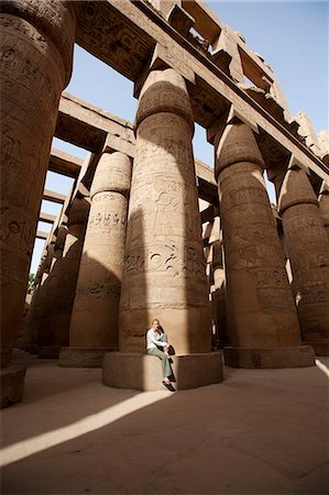 Ägypten, Karnak. Ein Tourist sitzt an der Basis einer massiven steinernen Spalte in die große Hypostyle-Halle. Stockbilder - Lizenzpflichtiges, Bildnummer: 862-03710916