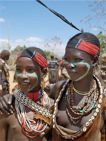 ethiopia girl - Two Hamar girl in fashionable dress at Turmi market. The Hamar are semi-nomadic pastoralists of Southwest Ethiopia whose women and girls wear striking traditional dress. Skins are widely used for clothing and heavy metal necklaces,bracelets and anklets form part of their adornments. Cowries are also popular yet the sea is 500 miles from Hamar country. Stock Photo - Rights-Managed, Code: 862-03711116