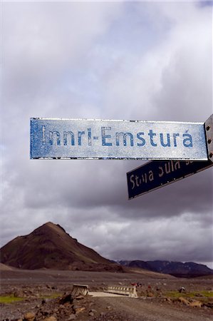 Iceland. Signpost in the middle of Iceland's blasted volcanic interior with an extinct cinder cone in the background. Part of the Laugavegur Ultra Marathon/ Adventure race course stretching from Landmannalaugar in the highlands to Thorsmork. Foto de stock - Con derechos protegidos, Código: 862-03711808