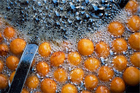 syrup - Cooking 'Gulab Jamun'Gulab jamun is a popular Indian sweet comprised of fried milk balls in a sweet syrup flavoured with cardamom seeds and rosewater or saffron. It may have originated from eastern India (Orissa and Bengal). Stock Photo - Rights-Managed, Code: 862-03712015