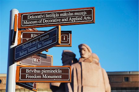 piazza del municipio - Tourist signpost with Statue of Latvian Red Riflemen in Town Hall square (Ratslaukums), Riga, Latvia Fotografie stock - Rights-Managed, Codice: 862-03712665