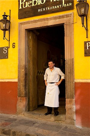 simsearch:862-03712902,k - Un homme debout devant un restaurant souriant dans une rue de San Miguel, au Mexique Photographie de stock - Rights-Managed, Code: 862-03712885