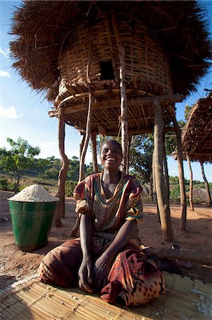 Malawi, Lilongwe, Ntchisi Forest Reserve. Dans l'ombre une jeune femme prépare la farine de mil pour sa famille. Photographie de stock - Rights-Managed, Code: 862-03713087