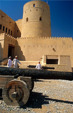 simsearch:862-03437387,k - Oman, Batinah, Rustaq. Omani boys stroll past a cannon in the grounds of Rustaq Fort, reputedly one of Oman's oldest forts. Fotografie stock - Rights-Managed, Codice: 862-03713128