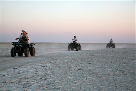 quads - Botswana, Makgadikgadi, Jack's Camp. Tourists race across the pans on quadbikes at sunset. Foto de stock - Con derechos protegidos, Código: 862-03736356