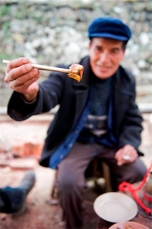 festival in village - China, Guizhou Province, Qingman Miao village, a man eating at a festival Stock Photo - Rights-Managed, Code: 862-03736541