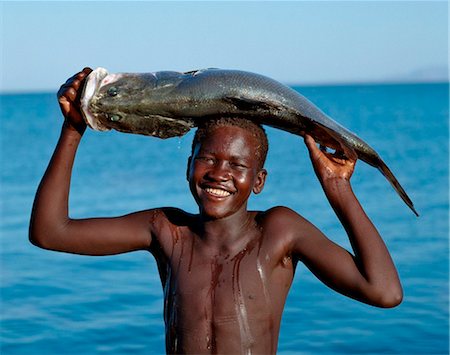 fishermen in africa - A happy Turkana boy carries home a Nile perch which he caught in Lake Turkana. Stock Photo - Rights-Managed, Code: 862-03736851