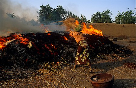 people burning africa - Mali, near Segou, Kalabougou. A woman adds kindling to a fire in which pottery - for which this village is famous - is baked. Stock Photo - Rights-Managed, Code: 862-03736915