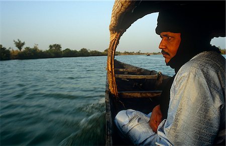 Mali. nahe Segou, Kalabougou. Ein Tuareg-Führer sitzt in einem kleinen Boot oder Piroge, Überquerung des Flusses Niger bei Kalabougou. Stockbilder - Lizenzpflichtiges, Bildnummer: 862-03736917