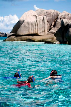seychelles - Seychelles. A mother and two children snorkel over shallow coral reefs surrounding the granite outcrops of the St Pierre Marine Park near Praslin. Stock Photo - Rights-Managed, Code: 862-03737092