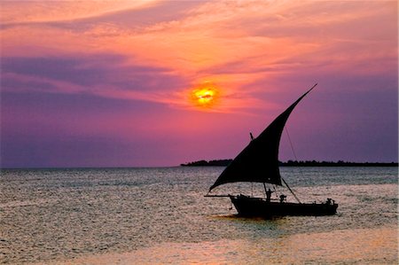 Tanzania, Zanzibar. A dhow sails back to Zanzibar harbour at sunset. Stock Photo - Rights-Managed, Code: 862-03737271