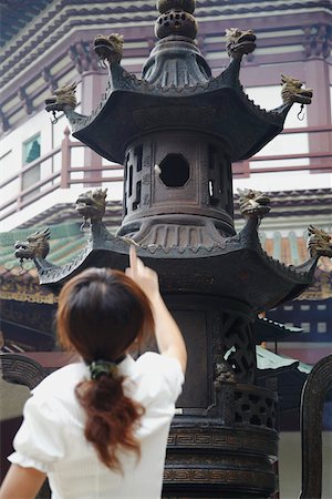 Woman throwing money into urn for luck, Liurong Temple, Guangzhou, Guangdong Province, China Stock Photo - Rights-Managed, Code: 862-03731078