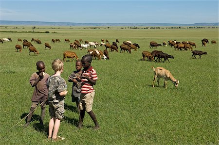 simsearch:862-08090669,k - Kenya, Masai Mara.  A young boy on safari meets Maasai children tending their herds of goats and sheep out on the plain. Stock Photo - Rights-Managed, Code: 862-03731730