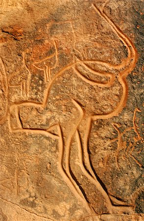 Libya, Fezzan, Messak Settafet. A petroglyph of an ostrich stands among the rocky outcrops of Wadi Mathendusch. Fotografie stock - Rights-Managed, Codice: 862-03731769