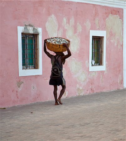 simsearch:862-03711647,k - Mozambique, Ihla de Moçambique, Stone Town. A man walks with his catch through the brightly-painted buildings Foto de stock - Con derechos protegidos, Código: 862-03731875