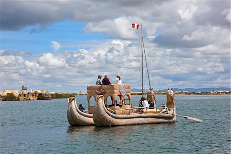 puno - Au Pérou, un bateau de grands roseaux utilisé par les touristes est rangs dans le chenal principal entre l'uniques des îles flottantes d'Uros sur le lac Titicaca. Photographie de stock - Rights-Managed, Code: 862-03732105