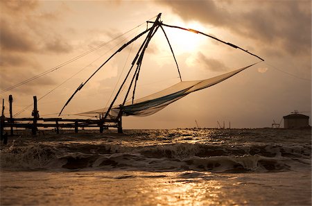 simsearch:614-02048520,k - Inde, Cochin. Un chinois traditionnel de pêche net, donc symbolique du Kerala, silhouetté sur le coucher du soleil. Photographie de stock - Rights-Managed, Code: 862-03807538