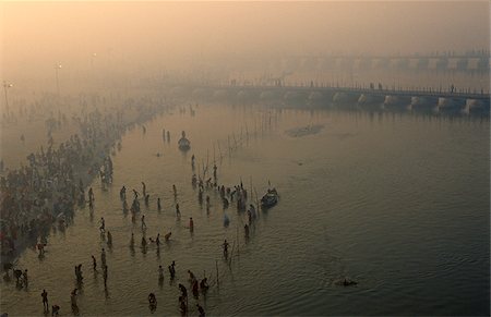 India, Uttar Pradesh, Allahabad. Hindu pilgrims bathe beside temporary pontoon bridges across the River Ganges built to help ease the vast numbers of pilgrims attending the celebrated Kumbh Mela festival held here every twelve years. Stock Photo - Rights-Managed, Code: 862-03807582