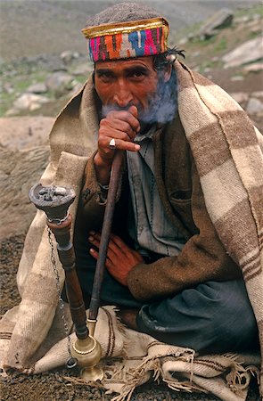 India, Himachal Pradesh, Chamba Valley. A Gaddi (semi-nomadic shepherd) from Chamba smokes a hookah, or water pipe, on the trail linking Kugti village, Kugti Pass and the summer grazing meadows of Lahaul. Fotografie stock - Rights-Managed, Codice: 862-03807623