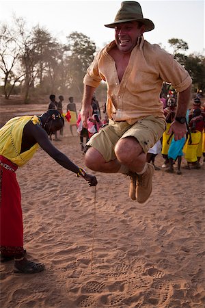 samburu - Kenya, Samburu District.  A tourist attempting to jump as high as a Samburu warrior, in the dry river bed of the Ewaso Nyiro. Foto de stock - Con derechos protegidos, Código: 862-03807768